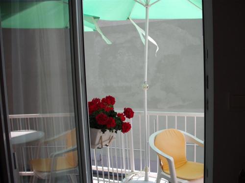 a balcony with a vase of flowers and a chair and an umbrella at Apart Hévízi Ház in Hévíz