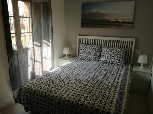 a bedroom with a large bed and a window at APARTAMENTOS POBRA-CASTELO in A Pobra do Caramiñal