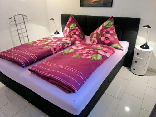 Cama con sábanas y almohadas de color púrpura y rosa en Ferienwohnung im Atelierhaus en Meersburg