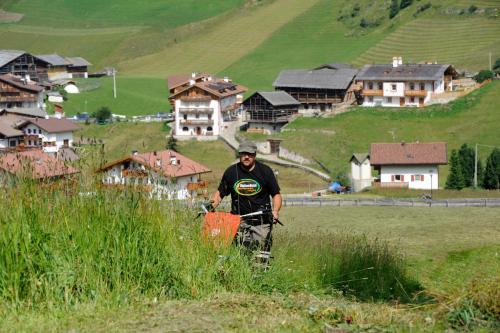 a man standing in a field of grass with houses at Agriturismo Maso Larciunei in Selva di Val Gardena