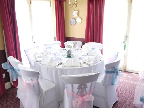 a white table with white chairs and a table with glasses at The Bell Hotel in Winslow