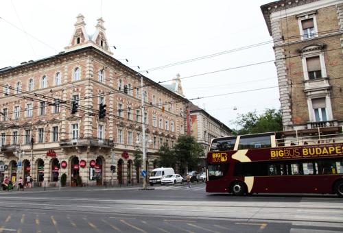 a red double decker bus driving down a city street at Brand New Apartment Budapest in Budapest