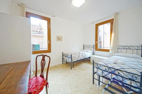 a bedroom with two beds and a desk and two windows at DolceVita Apartments N 372 in Venice