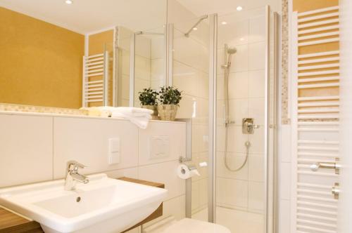 a white bathroom with a sink and a shower at GuestHouse Heidelberg in Heidelberg