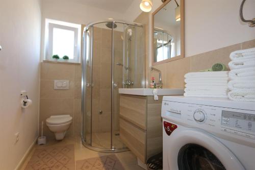 y baño con ducha y lavadora. en Apartments Baresic, en Šilo