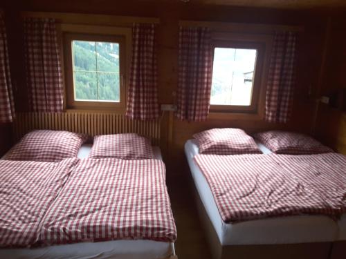 two beds in a room with two windows at Steinwandhütte in Stummerberg