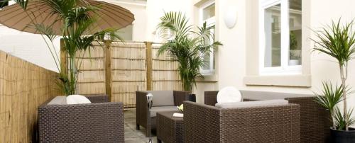 a patio with wicker chairs and palm trees in a building at GuestHouse Heidelberg in Heidelberg