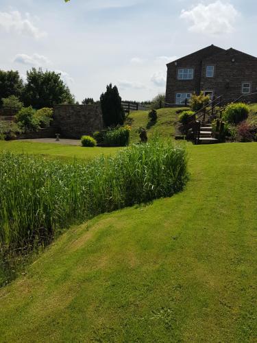 a large grassy yard with a house in the background at Grains Bar Hotel in Oldham