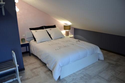 ein Schlafzimmer mit einem großen weißen Bett mit zwei Kissen in der Unterkunft Le Bon Etage in Fresnes-en-Woëvre