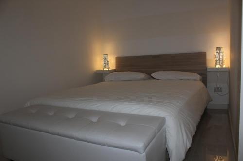 a bedroom with a large white bed with two lamps at La Maison in Vallata