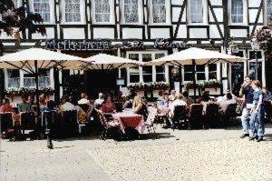 Un groupe de personnes assises à des tables avec des parapluies dans l'établissement Altstadtgasthof Krone, à Eschwege