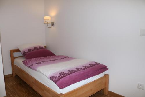 ein kleines Bett mit einer lila und weißen Decke darauf in der Unterkunft City Home- Business Apartment in Nürnberg