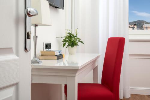 a red chair sitting next to a white desk with a window at Hotel Villa Garden in Sant'Agnello