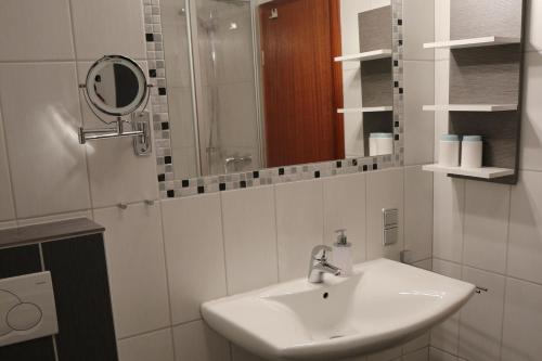 bagno bianco con lavandino e specchio di Gästehaus Preuss a Ellenz-Poltersdorf