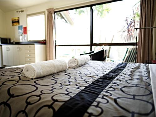 a bedroom with a bed with two rolled towels on it at Tairua Shores Motel in Tairua