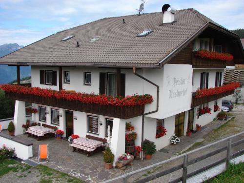a white building with red flowers in front of it at Pension Rastnerhof in Luson