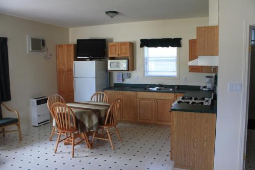 a kitchen with a table and chairs and a refrigerator at Sunny Beach Motel in Penticton