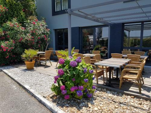 a patio with a table and chairs and purple flowers at Logis Boutique Hotel Novalis in Gradignan