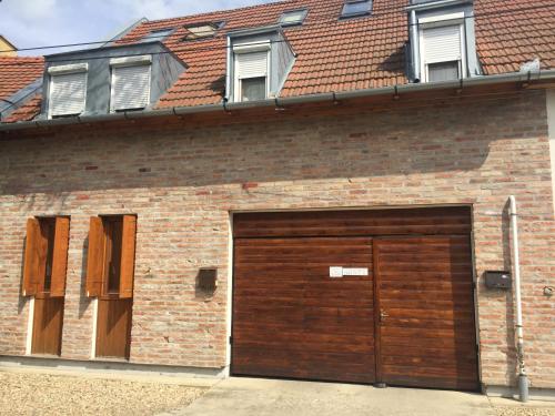 a brick building with a large wooden garage door at Bíbor Apartman in Gyula