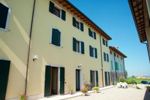 a large white building with green shuttered windows at Agriturismo Albarello in Sona
