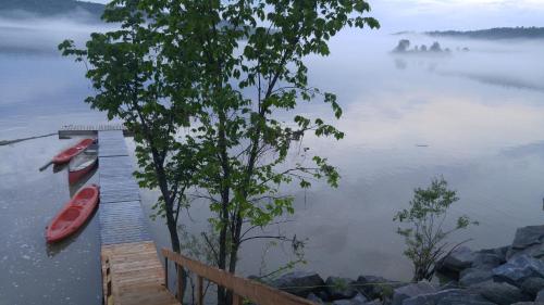 a dock with a red boat on a lake at Domaine de la Baie, Les Suites in Shawinigan