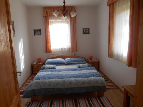 a bedroom with a bed with blue pillows and a window at Vendégmarasztaló Porta in Szalafő