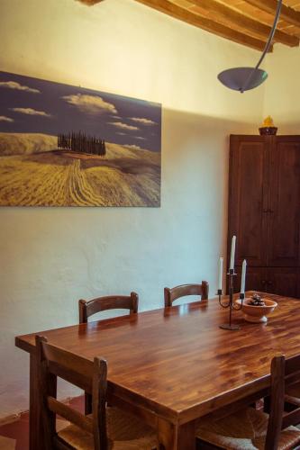 a wooden dining room table with chairs and a painting on the wall at Agriturismo Palazzo Val Del Sasso in Villastrada