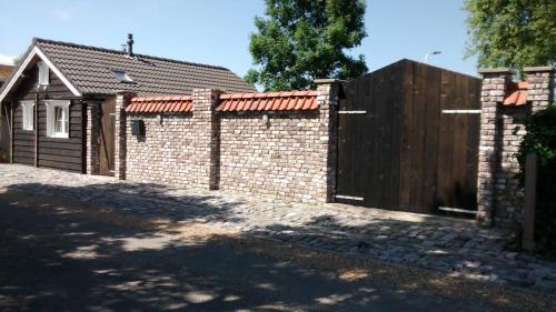 a brick fence with a wooden gate in front of a house at Dijkwoning Cadzand in Cadzand