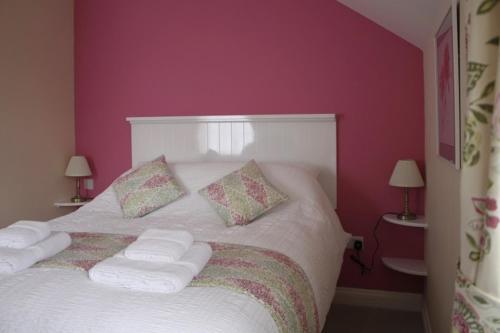 a bedroom with a white bed with pink walls at The Anchor Inn in Thornbury