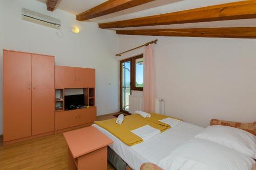 a bedroom with a large bed with a yellow blanket on it at Apartments Bilo in Primošten