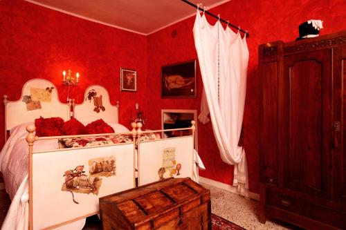 a bedroom with red walls and a bed with a wooden trunk at C'era una Volta in Perledo