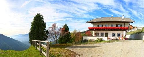 a house on the side of a hill with flowers at Pension Rastnerhof in Luson