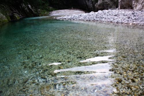 a body of water with rocks in the water at Apartment Pri Bricu in Kobarid