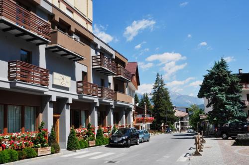 a street with cars parked next to a building with flowers at Serendipity Hotel in Sauze dʼOulx