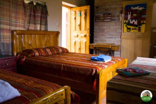 a bedroom with two beds and a door to a room at Loma Wasi Alojamiento Rural Indígena en Cotacachi in Cotacachi