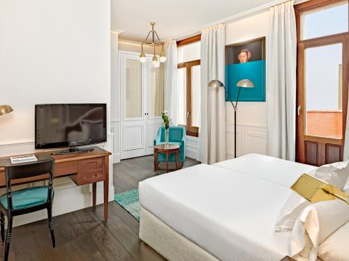 a hotel room with a large bed and a television at Boutique Hotel H10 Villa de la Reina in Madrid