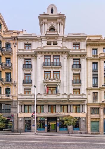 a large building on a street in front of a building at Boutique Hotel H10 Villa de la Reina in Madrid