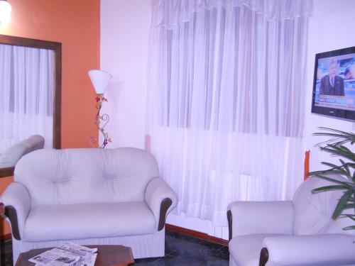 a living room with two chairs and a tv at Dennisse Hotel in Victoria