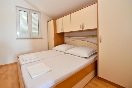 a small bedroom with a bed and a window at Milka Appartements in Stara Novalja