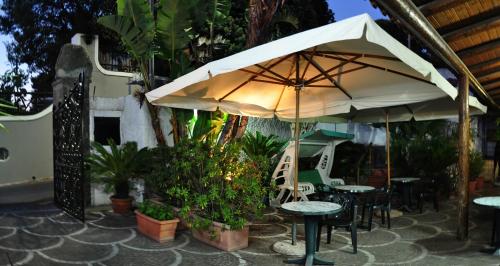 a patio with tables and an umbrella and plants at Casa Cigliano in Ischia