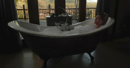 a woman sitting in a bath tub in a room at Etali Safari Lodge in Madikwe Game Reserve