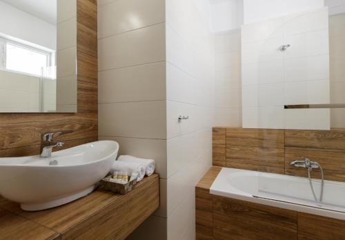 ein Badezimmer mit einem weißen Waschbecken und einer Badewanne in der Unterkunft Asteria Hotel in Tolo