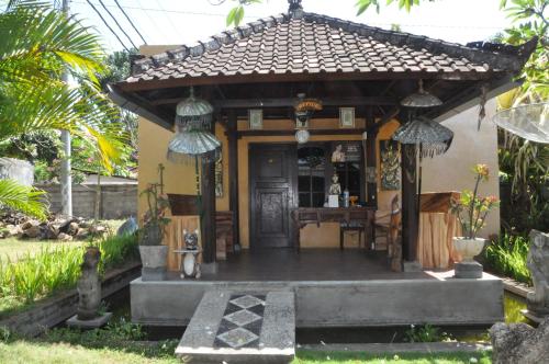 a small house with a porch in a garden at Pondok Bali Sea View Bungalow in Lovina