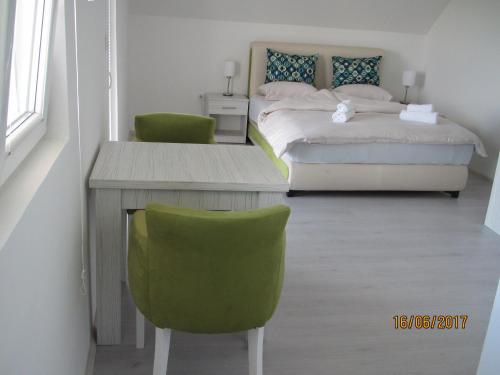 a bedroom with a bed and a desk and a green chair at Guest House Baranin Pitomine in Žabljak