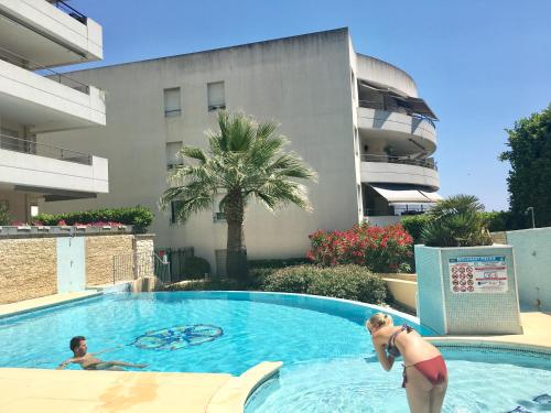 une femme debout dans une piscine à côté d'un bâtiment dans l'établissement Mandelieu centre -Les Hauts de Lérins, à Mandelieu-la-Napoule