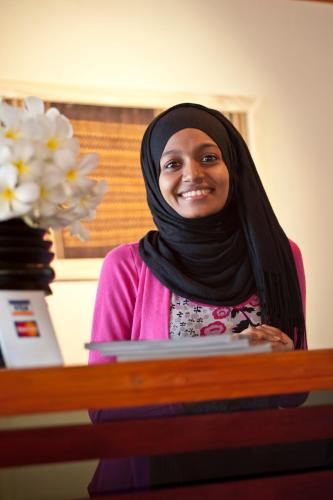 a woman sitting at a desk with a laptop at Stingray Beach Inn in Maafushi