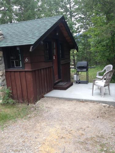 a small cabin with a grill and a bench at Addison's Bungalows in Brisco