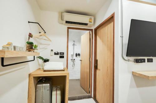 a bathroom with a toilet and a tv and a suitcase at Vann Bangkok Boutique House in Bangkok
