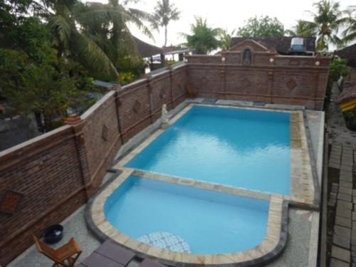a large blue swimming pool in a building at Mandhara Chico Bungalow in Lovina
