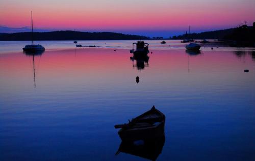 a boat sitting in the water with a sunset at Athina-Milina in Milína